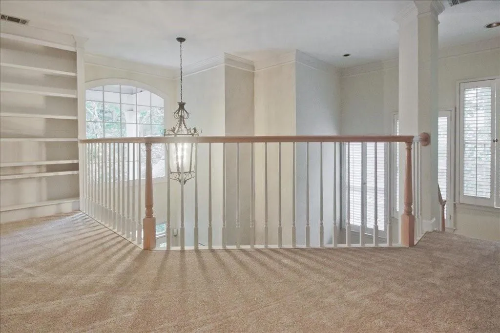 Corridor with carpet floors, crown molding, and a chandelier