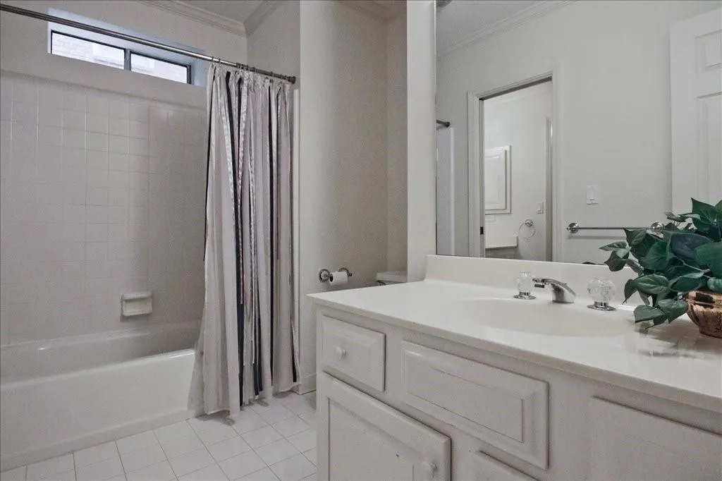 Bathroom featuring shower / bath combo, light tile patterned floors, ornamental molding, and vanity