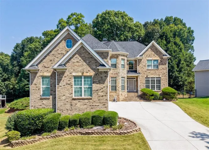 Brick facade residence featuring a prominent gabled roofline, stone accents, and a concrete driveway