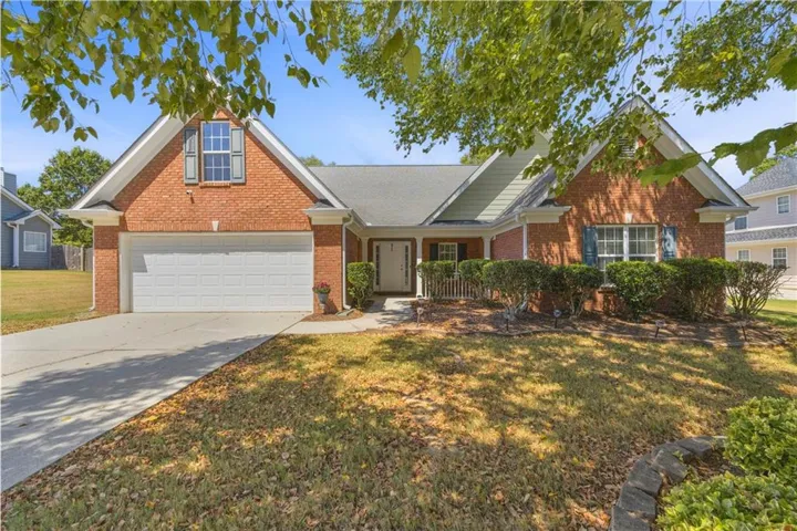 Brick exterior, gabled roofline, attached two-car garage, established landscaping, and a covered front entry
