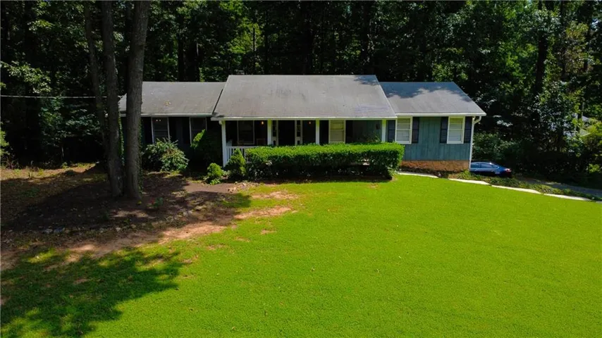 Expansive front lawn, mature trees, and dense foliage surround the property