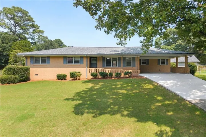 Single-story brick home featuring a gray shingle roof and a concrete driveway