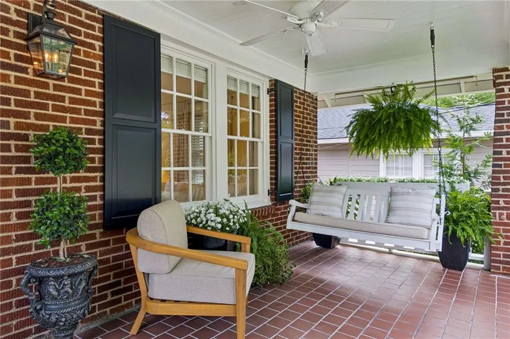 Covered front porch featuring brick siding, a ceiling fan, and tiled flooring