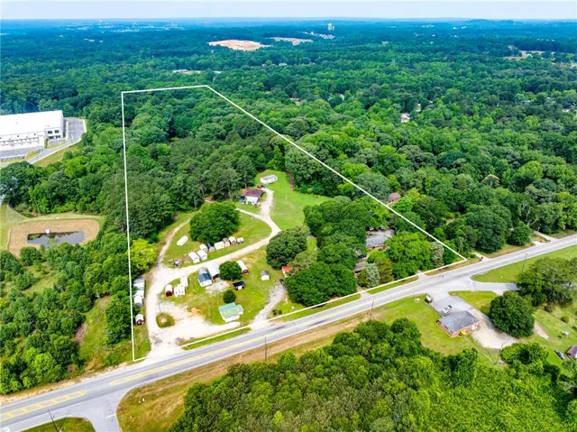 Aerial view of property and surrounding area with a heavily wooded area and property parcel outlined