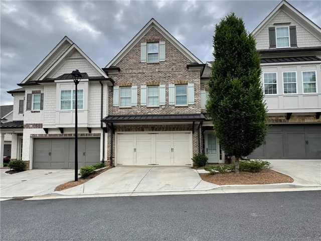Brick and siding exterior featuring gabled roofs, decorative shutters, and multiple garage bays
