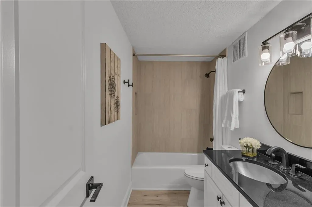 Bathroom with a textured ceiling, vanity, and shower / tub combo with curtain