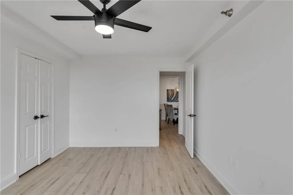 Empty room with ceiling fan and light wood-style floors