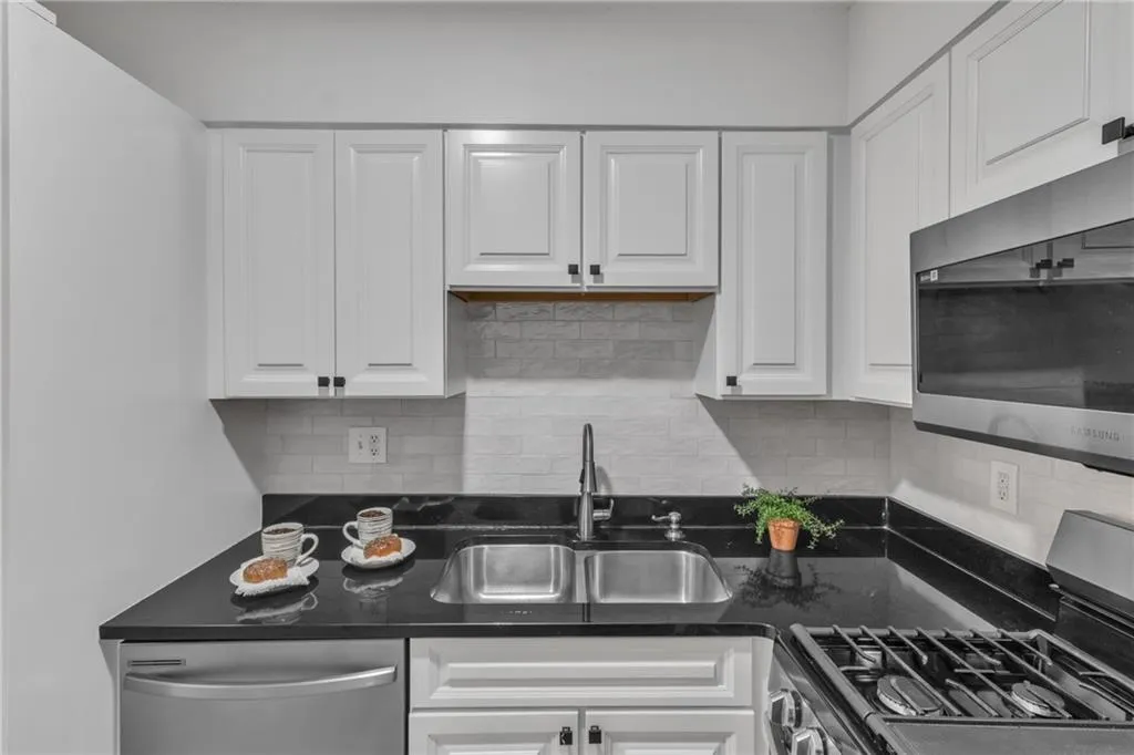Kitchen featuring appliances with stainless steel finishes, white cabinetry, and backsplash