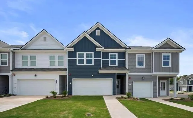 Craftsman inspired home with board and batten siding, an attached garage, a front lawn, and driveway