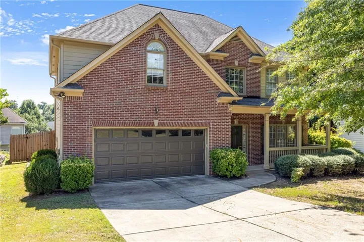 Brick exterior with a shingle roof and a two-car garage