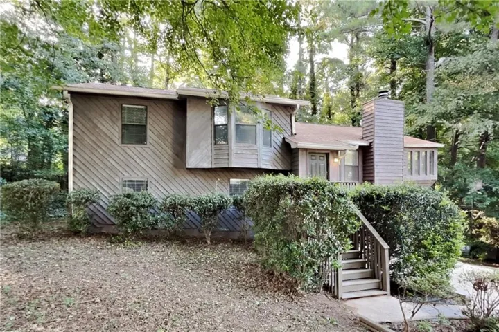 Split-level residence featuring diagonal wood-finish siding and a prominent chimney structure