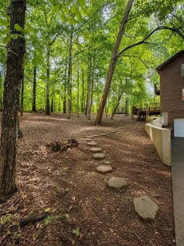 Wooded backyard with mature trees, stone stepping path, and multi-level decking