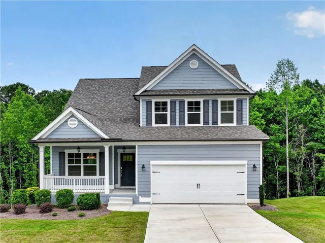 Two-story residence featuring light blue siding, a covered front porch with white railings, and a two-car garage