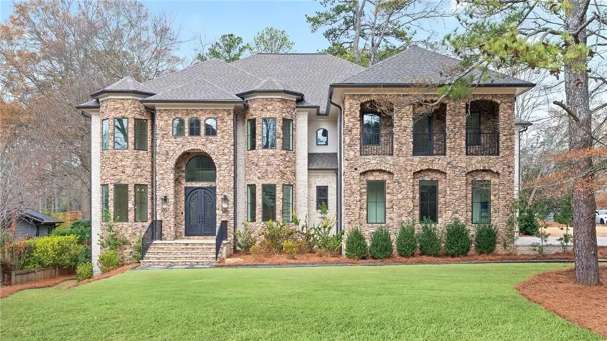 French country inspired facade featuring a front yard, stone siding, and roof with shingles