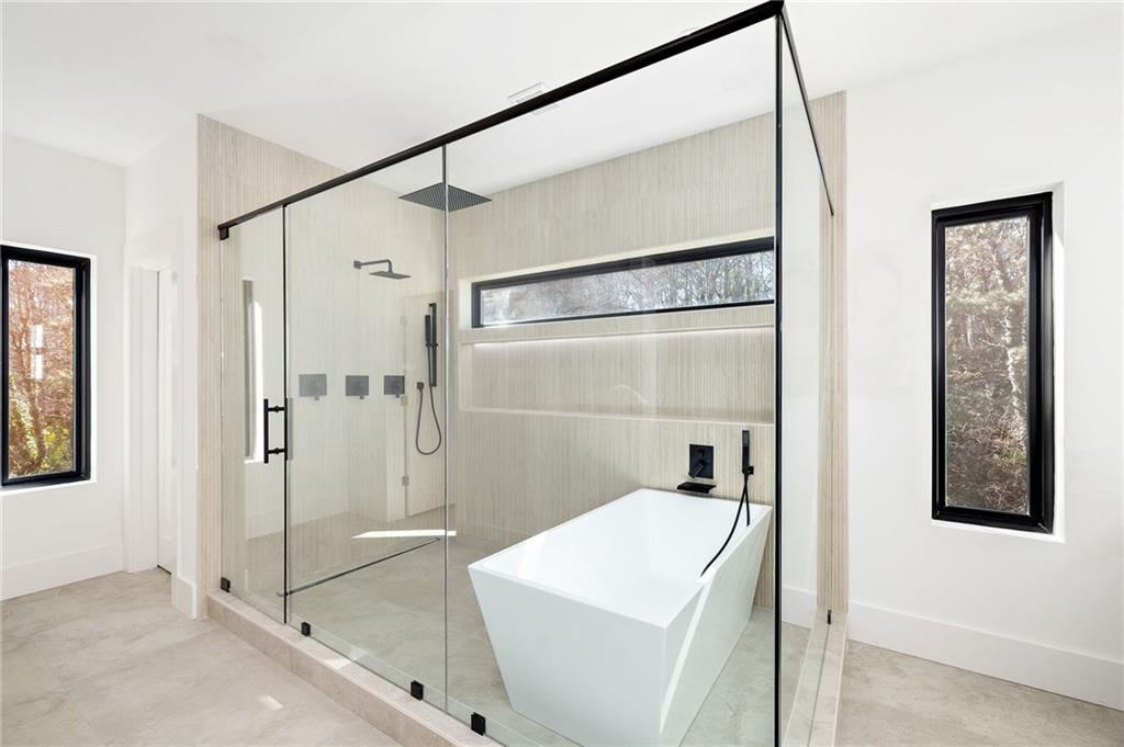 The spa-grade bathroom features featuring high-end fixtures, a spacious walk-in shower, a luxurious soaking tub, and designer finishes that create a serene atmosphere.