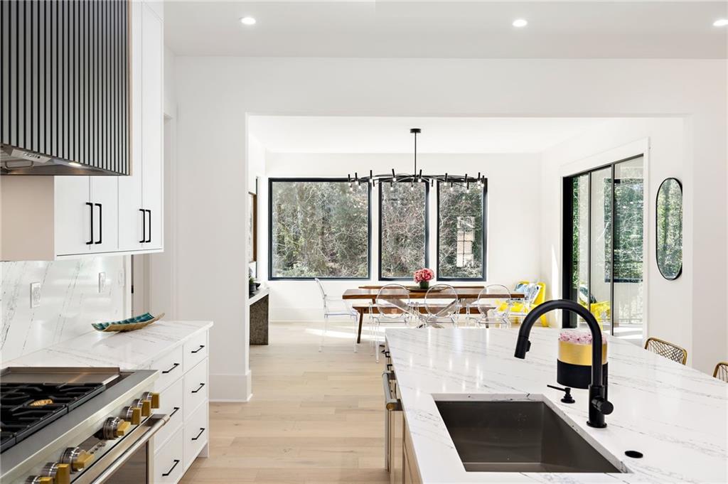 The chef’s kitchen is a culinary delight, equipped with top-of-the-line stainless steel appliances, custom cabinets, quartz countertops, a spacious island, a meticulously designed walk-in pantry, and an open dining room perfect for entertaining.
