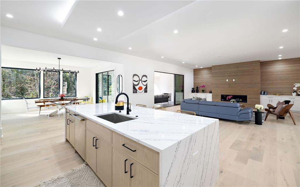 The chef’s kitchen is a culinary delight, equipped with top-of-the-line stainless steel appliances, custom cabinets, quartz countertops, a spacious island, a meticulously designed walk-in pantry, and an open dining room perfect for entertaining.