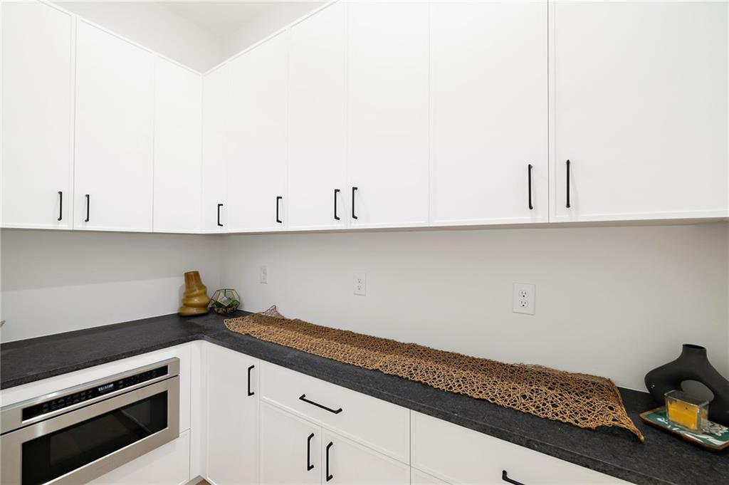 The chef’s kitchen is a culinary delight, equipped with top-of-the-line stainless steel appliances, custom cabinets, quartz countertops, a spacious island, a meticulously designed walk-in pantry, and an open dining room perfect for entertaining.