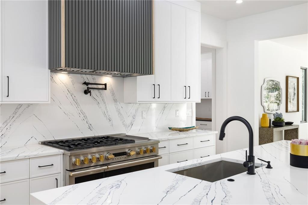 The chef’s kitchen is a culinary delight, equipped with top-of-the-line stainless steel appliances, custom cabinets, quartz countertops, a spacious island, a meticulously designed walk-in pantry, and an open dining room perfect for entertaining.