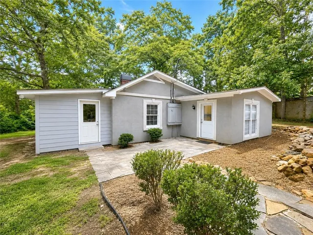 Paved patio area, stucco exterior, siding accent, mature landscaping, and stone walkway