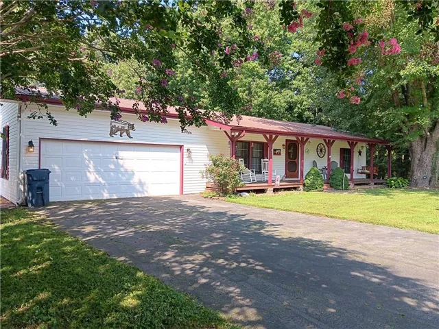 White siding exterior with a two-car garage, covered front porch, and red trim accents