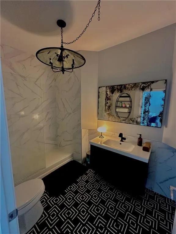 Full bath with vanity, a walk in shower, and a chandelier