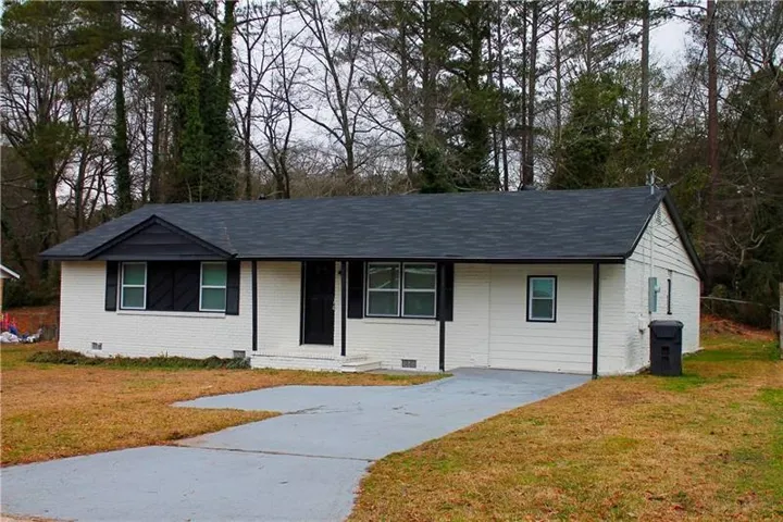 Ranch-style home with a front yard, brick siding, and roof with shingles