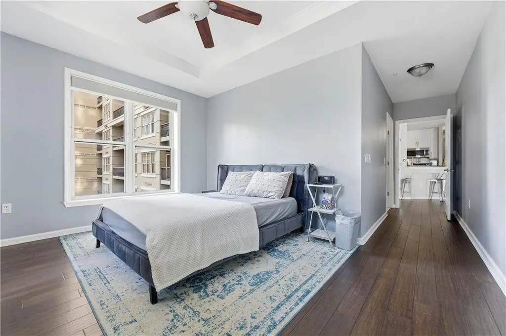 Bedroom featuring dark wood-style flooring, ceiling fan, and a tray ceiling