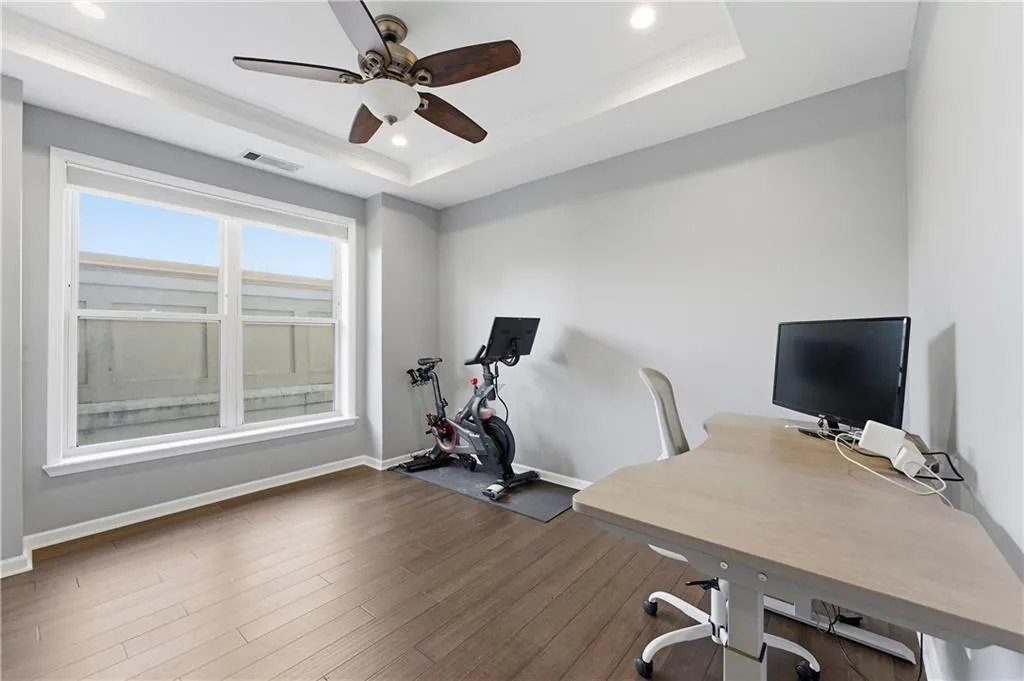Office area featuring wood finished floors, a ceiling fan, recessed lighting, and a tray ceiling