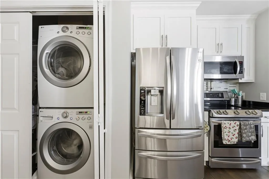 Laundry area featuring stacked washer and clothes dryer and dark wood finished floors