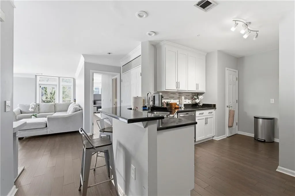Kitchen featuring white cabinetry, a peninsula, a breakfast bar area, dark wood-style flooring, and ornamental molding