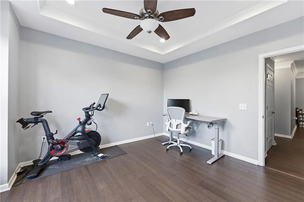 Office featuring ornamental molding, a raised ceiling, dark wood-style floors, a ceiling fan, and recessed lighting