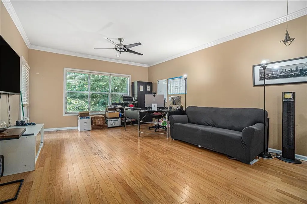 Living room with light wood-type flooring, a ceiling fan, and ornamental molding