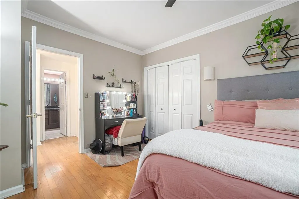Bedroom with a closet, crown molding, light wood-style flooring, and a ceiling fan