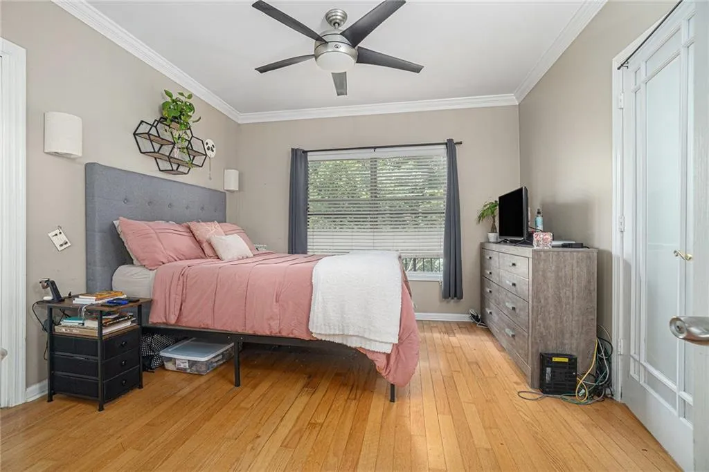 Bedroom featuring light wood-type flooring, crown molding, and ceiling fan