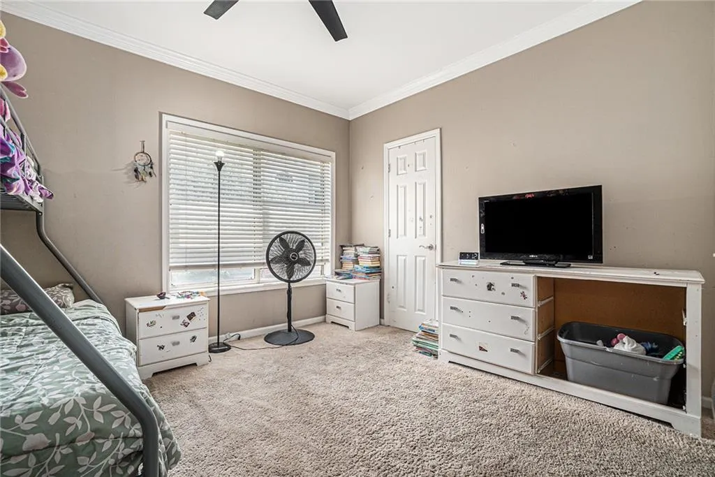 Bedroom featuring carpet flooring, ornamental molding, and a ceiling fan