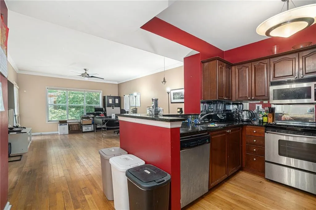 Kitchen with stainless steel appliances, light wood-style floors, ornamental molding, a ceiling fan, and dark countertops