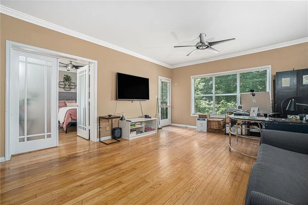 Living room featuring ornamental molding, a ceiling fan, light wood-style flooring, and an office area