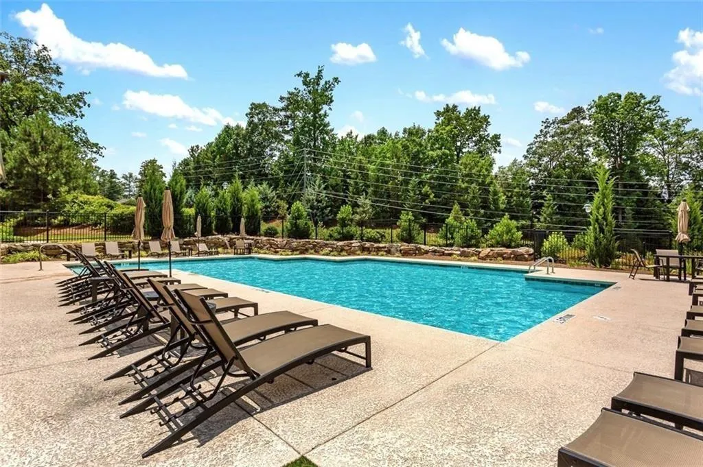 Community pool featuring view of scattered trees and a patio area