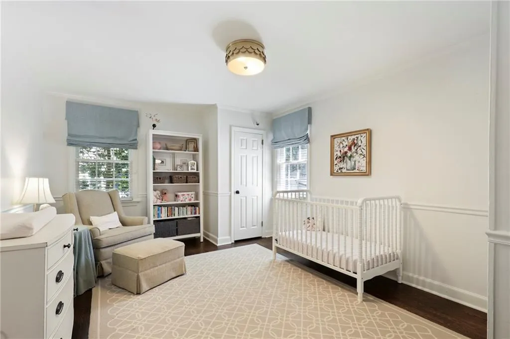 Bedroom featuring crown molding, wood finished floors, and a crib