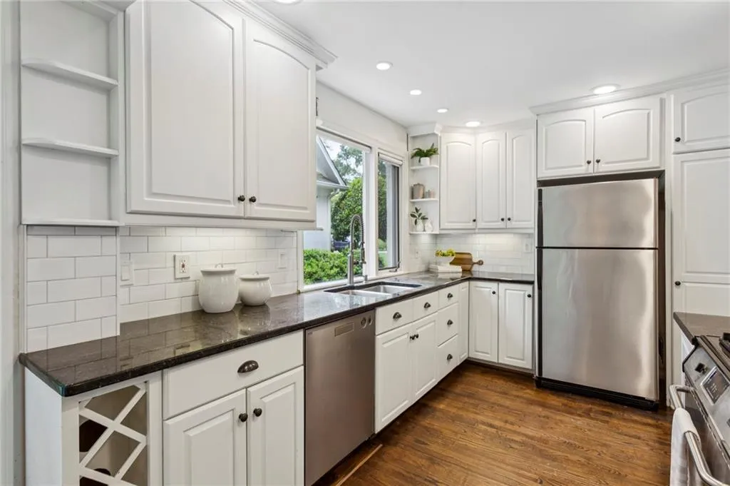 Kitchen with open shelves, stainless steel appliances, white cabinets, dark wood-style flooring, and recessed lighting