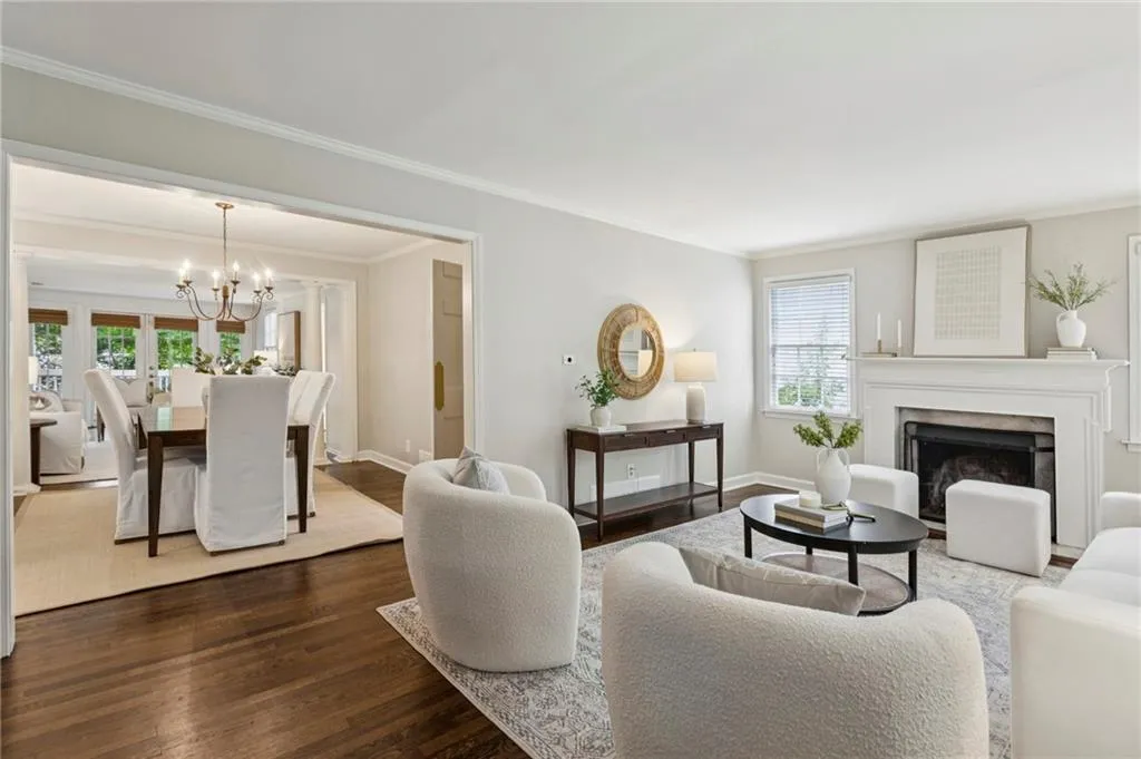 Living room with crown molding, dark wood-style floors, a high end fireplace, and a chandelier