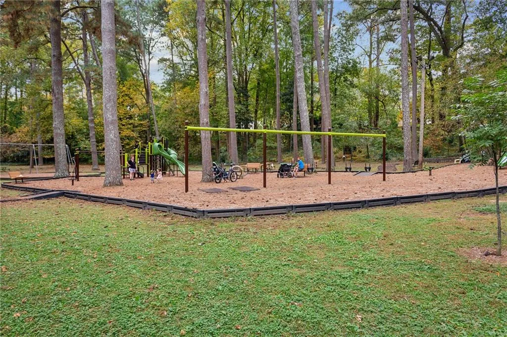 Communal playground with a lawn and view of wooded area