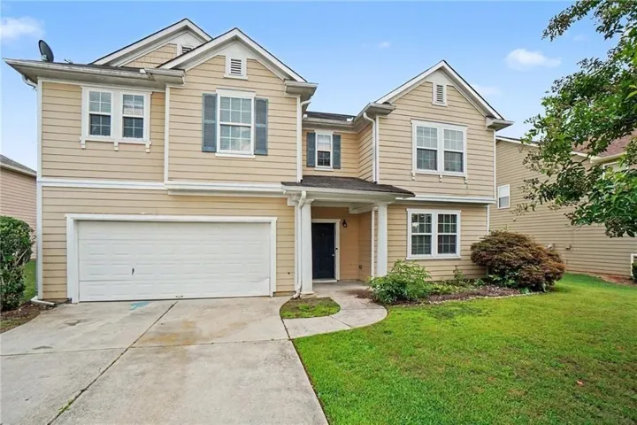 Two-story residence featuring light-colored siding, a two-car garage, and a concrete driveway