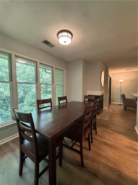 Dining room featuring wood-type flooring, a textured ceiling, and a healthy amount of sunlight
