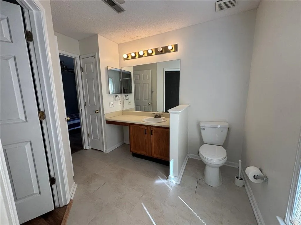 Bathroom with a textured ceiling, toilet, tile patterned flooring, and vanity