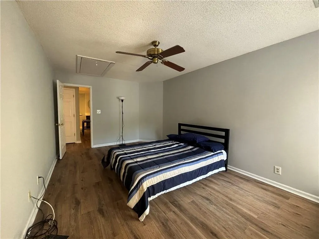 Bedroom with ceiling fan, wood-type flooring, and a textured ceiling