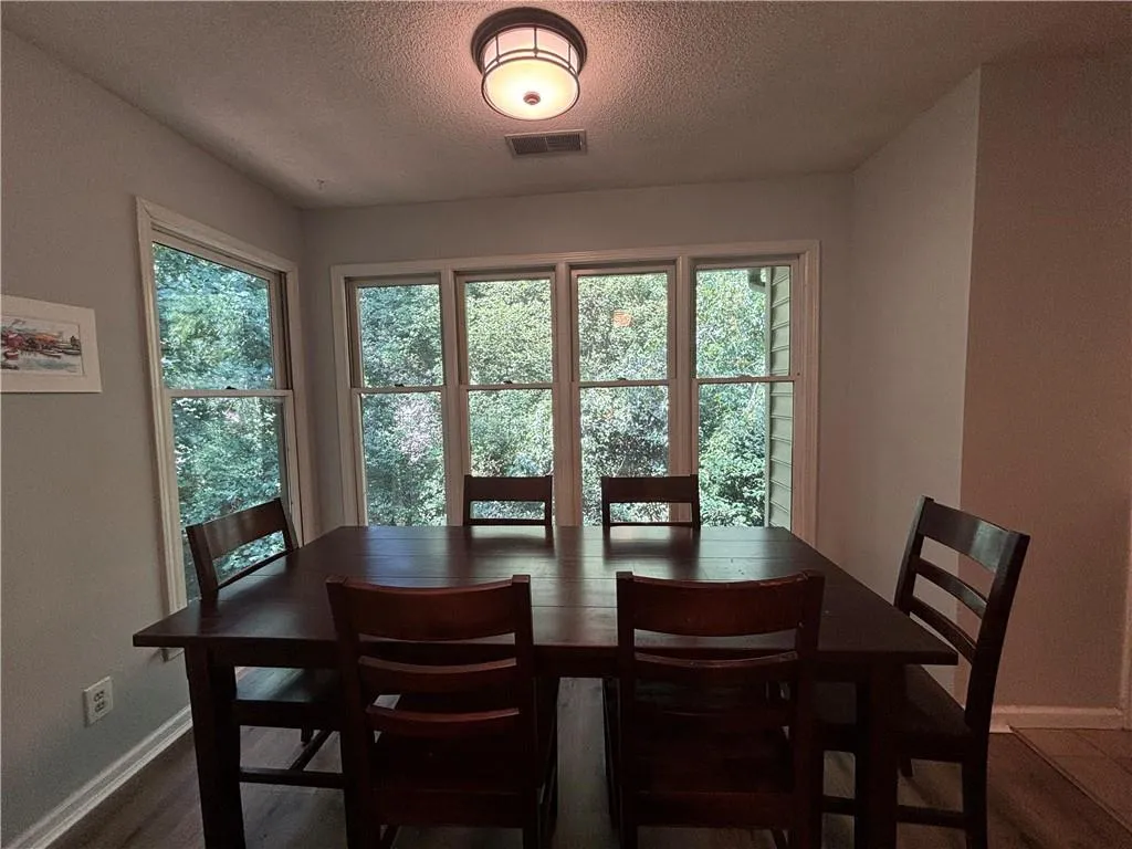 Dining room with hardwood / wood-style flooring, plenty of natural light, and a textured ceiling