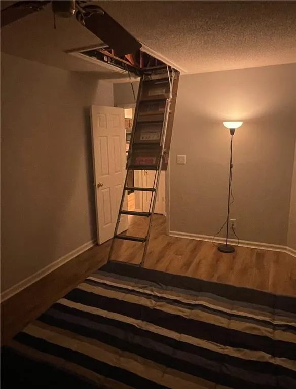 Stairs featuring a textured ceiling and hardwood / wood-style floors