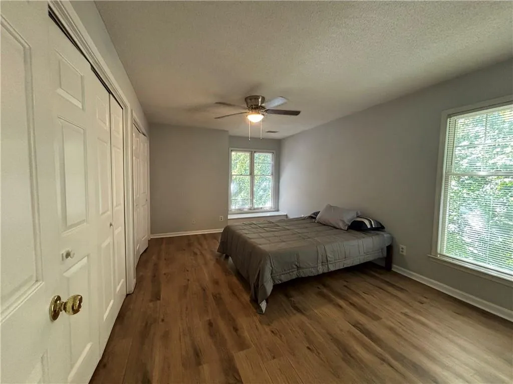 Bedroom with a textured ceiling, ceiling fan, multiple windows, and dark hardwood / wood-style flooring